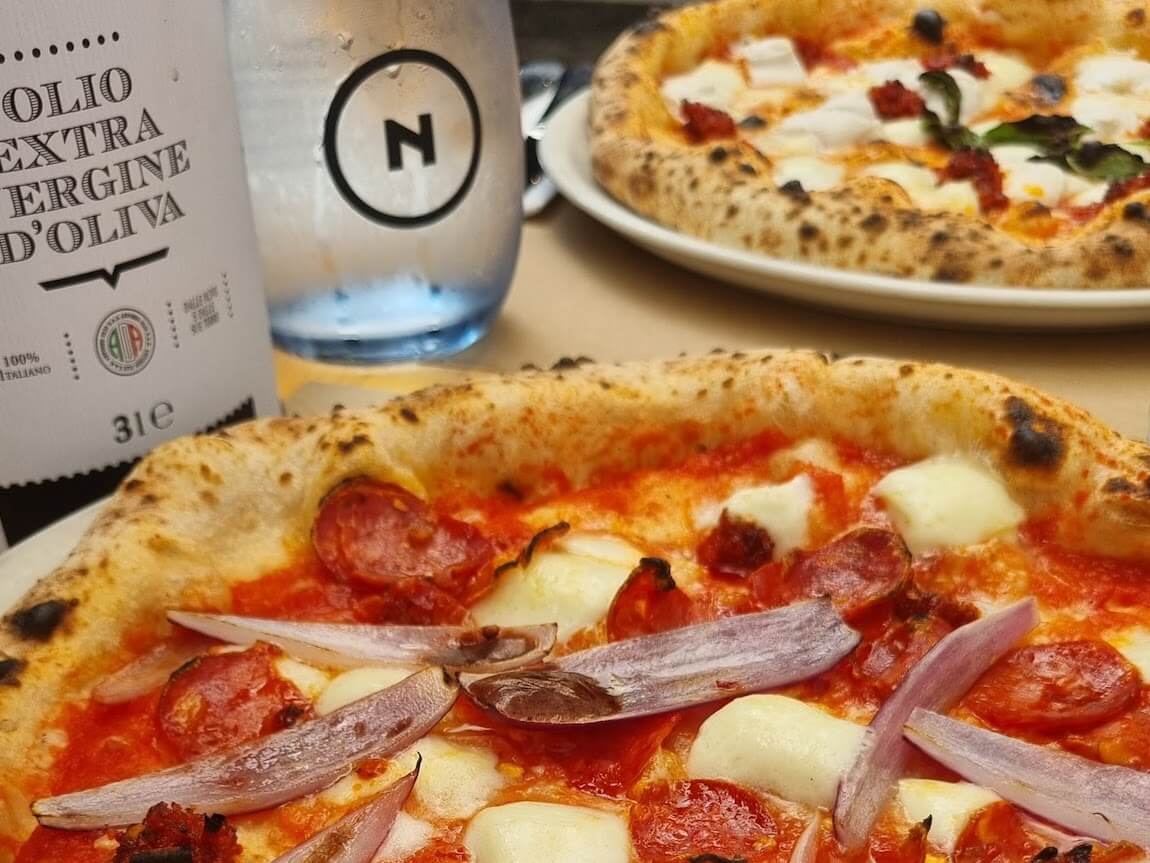 Pizza, stół i oliwa w pizzerii Nolio, Kraków - ranking najlepsza pizza w Krakowie