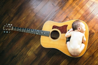 Gambar bayi lucu imut tidur di atas gitar