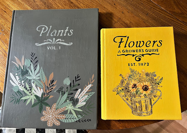 Photo of old books painted with chalk paint, stenciled with a botanical stencil, and decorated with decor transfers.