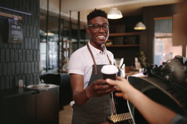 Barista serving customers inside coffee specialty shop.