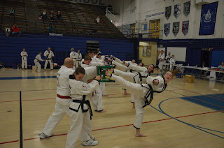 Four martial arts girls using teamwork to break boards