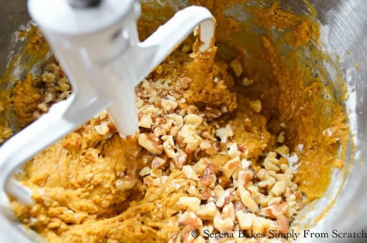 Pumpkin Bread batter with walnuts added in a stainless steel mixing bowl.