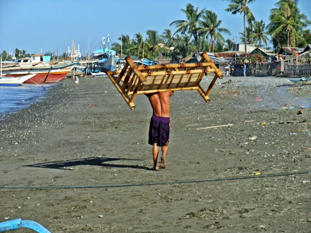 man carrying a bamboo sofa on the beach of San Jose Occidental Mindoro