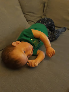 Reborn Anton makaa sohvalla käsi otsaa vasten. Päällä on vihreä t-paita ja jalassa siniset pitkät housut. Anton katsoo eteensä ja vaikuttaa voipuneelta tai ajatuksiin vaipuneelta.