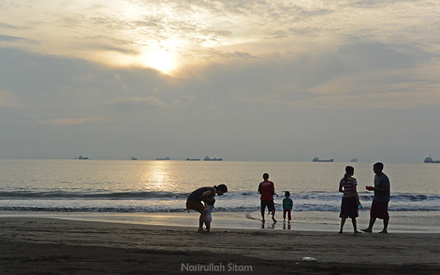 Pengunjung menikmati waktu pagi di pantai bersama keluarga