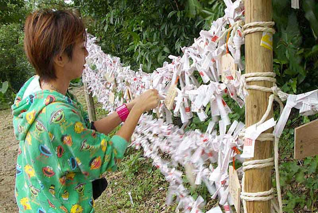 Girl tying a bad New Year's fortune to fence