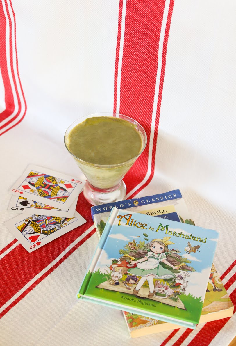 Pudding in a conical glass container and a red and white striped background, with both Alice in Matchaland and Lewis Carroll's books in background