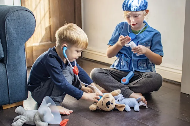 Siblings playing with cuddly toys as pretend vets to prompt make believe play