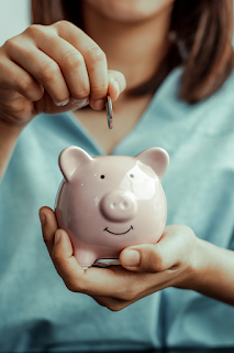 A woman holding a piggy bank on one hand and saving a money in it with the other