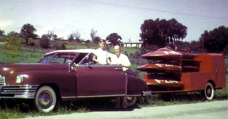 1955 photo of a Packard and it's loaded trailer of hydroplanes that is a