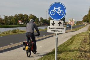 fietser met helm, van achteren gezien, achter hem langs het fietspad een bord met 'speed pedelecs toegestaan'