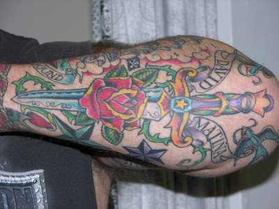 Large colorful dagger tattoo on forearm.