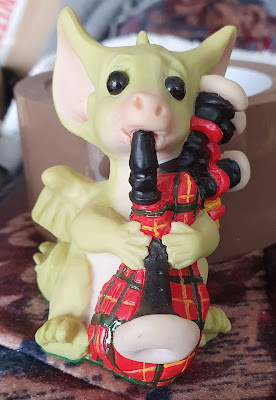 Scottish pocket dragon model wearing a kilt and playing babpipes