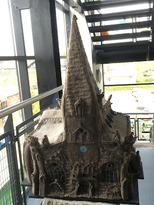 photograph of a model of a church, crafted from grey wool