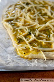 Image of Easy Chile Relleno Pizza ready to bake, with egg mixture spilling onto parchment paper