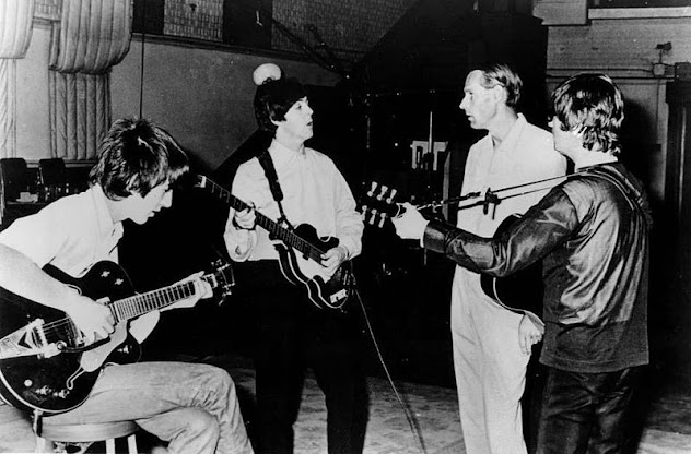Martin can be seen standing second from the right in the studio with the Beatles during the mid-1960s.