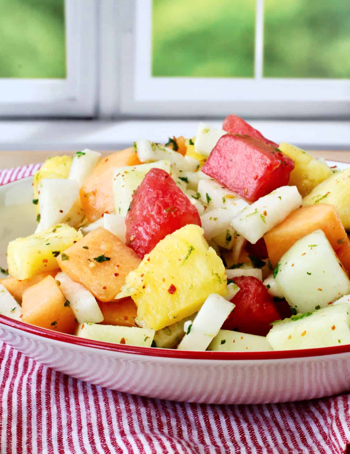 Melon, Jicama, and Pineapple Salad in red rimmed bowls.