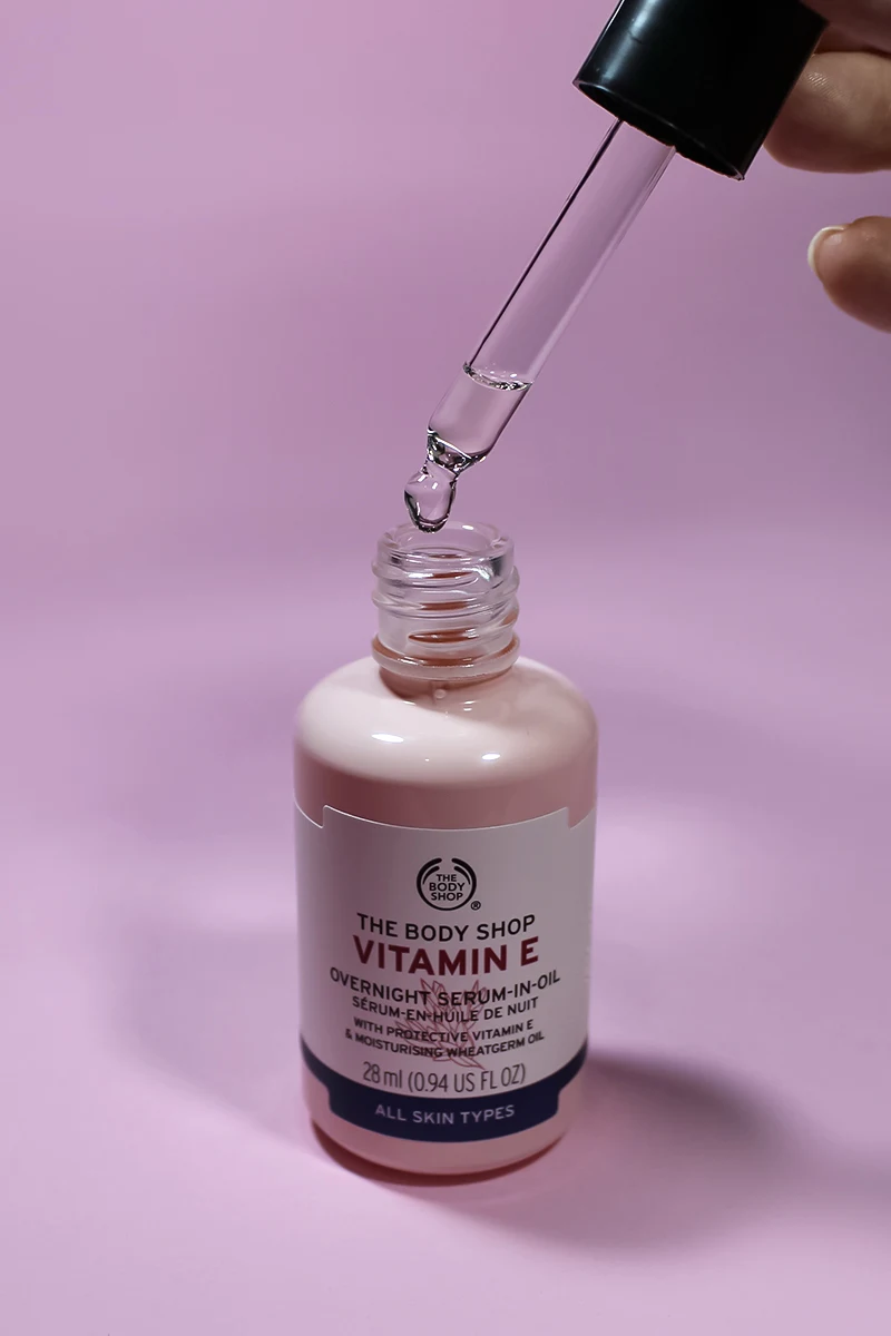 close-up of oil serum by the body shop on a plain, pink background