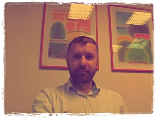 Piotr Krompiewski known as Kromproom sitting in an open office and behind him two hanging paintings painted by Milan Kaplan, owner of PROEBIZ