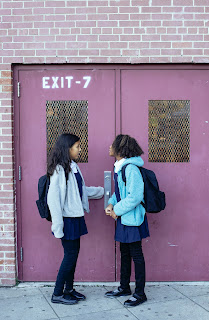 Two girls standing by the doorway to their class