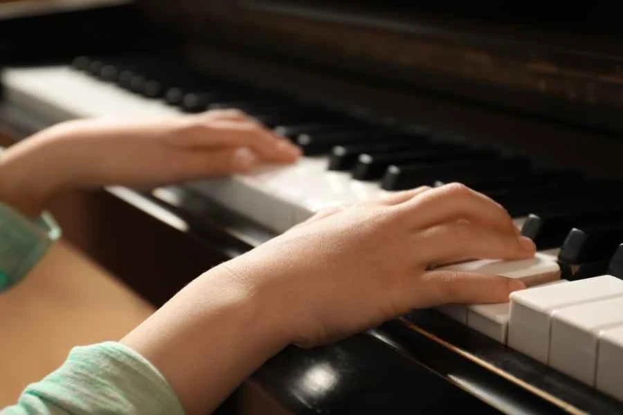 Close up of a child playing the piano. Stock image from Canva Pro