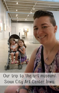 Haley McAndrews and her two young daughters at an art gallery. Text "Our trip to the art museum! Sioux City Art Center, Iowa"