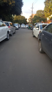 Automobile pass through lined up cars on both sides of street