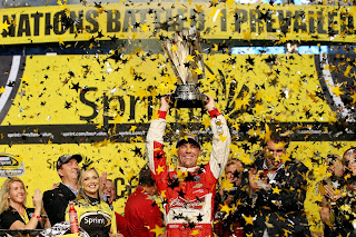 Kevin Harvick at the podium lifting the 2014 NASCAR Sprint Cup Series Championship trophy.