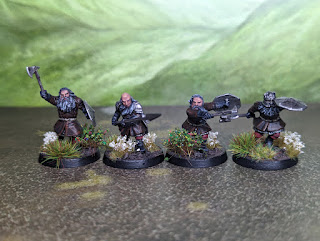 Four dwarf minis, painted with brown armour and grey beards