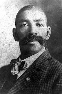 Black and white photo shows a portrait of an elegantly dressed man in suit and tie.