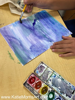 a student painting cool colored watercolors on their paper