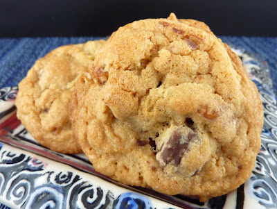 Salted Caramel Truffle Cookies- a variation on a chocolate chip cookie, with added pretzels and mini salted caramel truffles. Photographed on a white plate with pink boarder and blue swirls