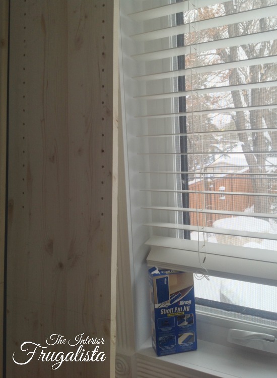 Using a handy Kreg Shelf Pin Jig to make holes for adjustable shelves on DIY bedroom built-in bookcase.