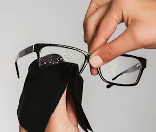 Image description: cleaning glasses while holding them from the bridge