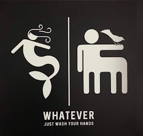 A bathroom door sign, in the style of the stick figure signs normally used to indicate Men or Women on public restroom doors, but instead of saying 'Men' or 'Women,' it includes a stick figure mermaid and a stick figure centaur with a bird perched on its hand, with the text, 'Whatever, just wash your hands.'