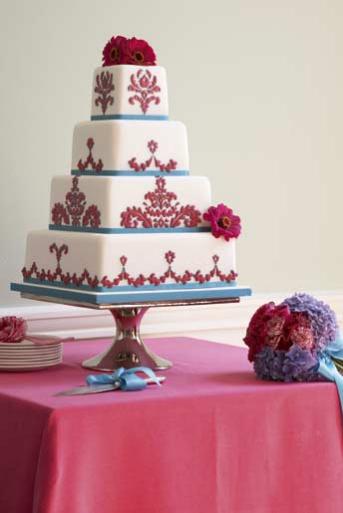 Four tier white cake with delicate red damask pattern red gerbera flowers 