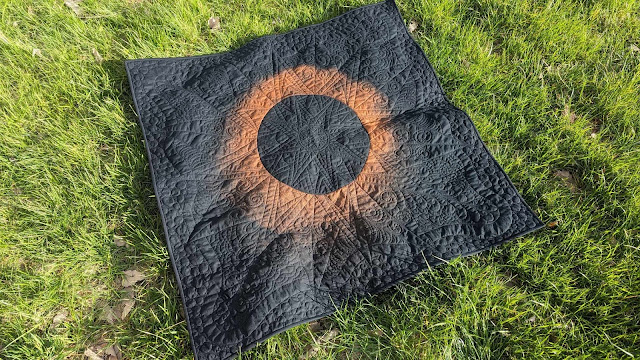Solar eclipse quilt made by bleaching black fabric