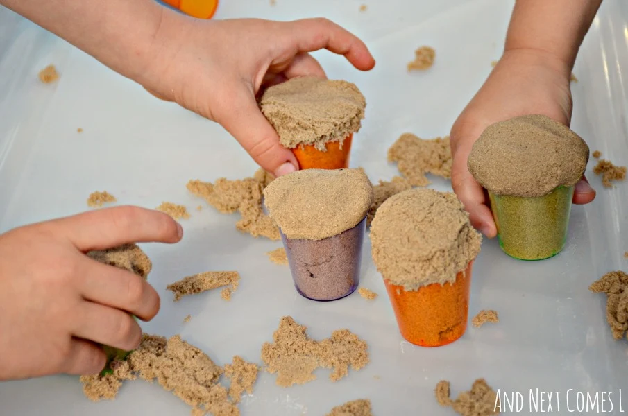 Fine motor activity using kinetic sand and colorful cups that's perfect for toddlers and preschoolers