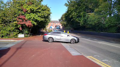 Another red continuous junction treatment with a grey car leaving the side street over it.