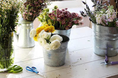 Flores en cubos de zinc sobre una mesa de trabajo 