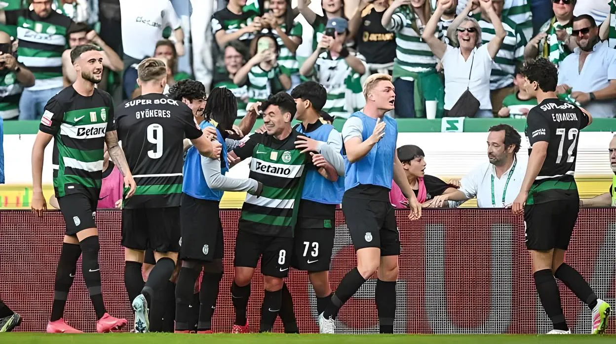 Jogadores do Sporting comemorando um gol em um jogo de futebol contra vitória FC, com torcida animada ao fundo. Momento de alegria e união da equipe.