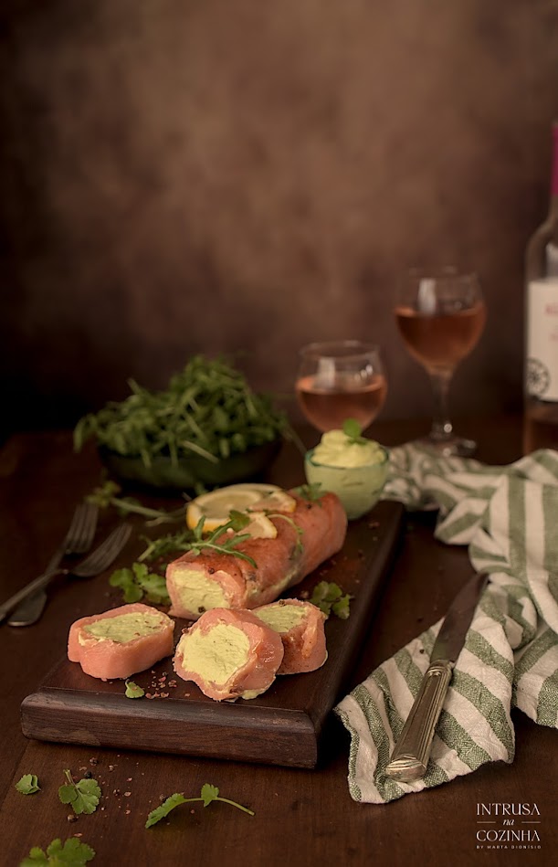 Rolo de salmão fatiado acompanhado de salada e copos de vinho rosé