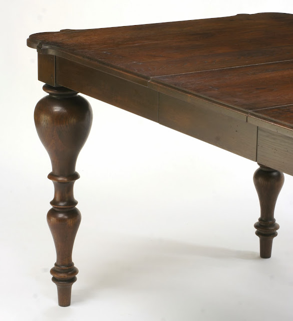 solid oak extension dining table with antique walnut finish has dramatic turned legs