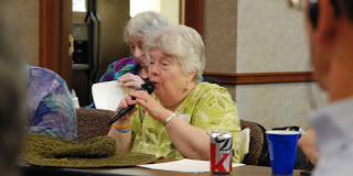 Nancy Webb, a light-skinned woman, using a microphone, speaks to AMD meeting