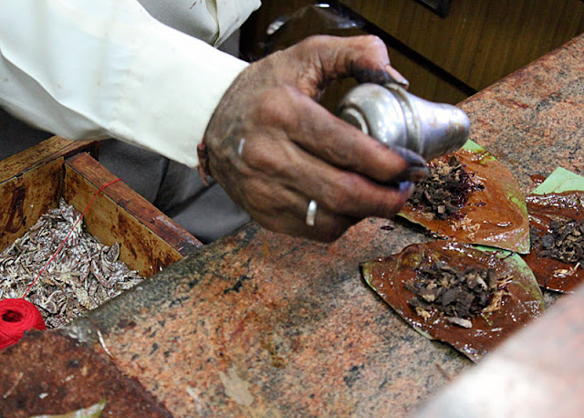 paan maker adding spices to a betel nut leaf