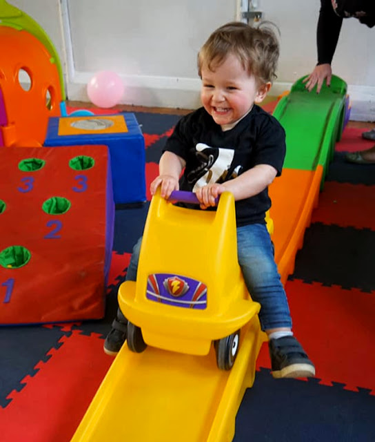 image shows a toddler riding on a small plastic roller coaster