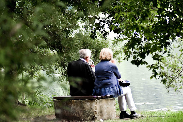 Casal idoso, sentados em um banco sob árvores