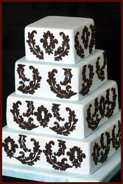 Elegant three tier square wedding cake with damask pattern and black satin 