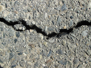 A close up of a crack in an asphalt surface, running left-right.