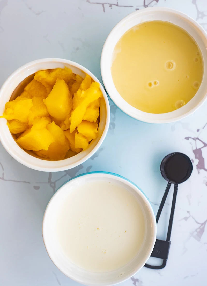 A picture of the ingredients needed to make mango ice cream with condensed milk.